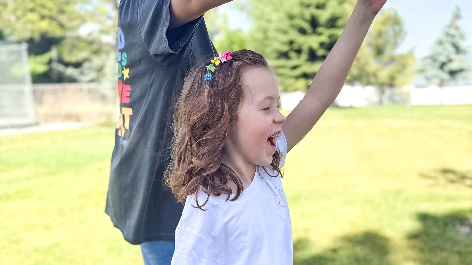 Child being lifted by an adult in a grassy outdoor setting